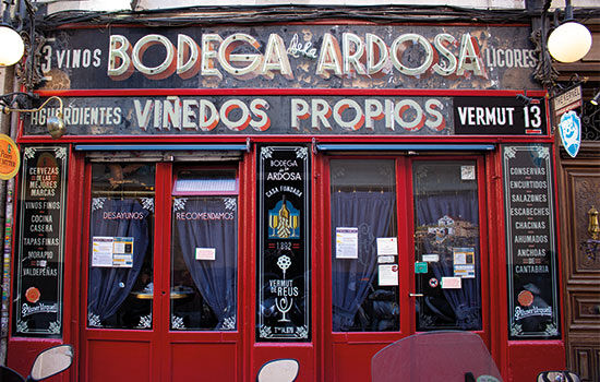 The bright red vintage facade of Bodega de La Ardosa is covered in items from its menu of Spanish tapas.