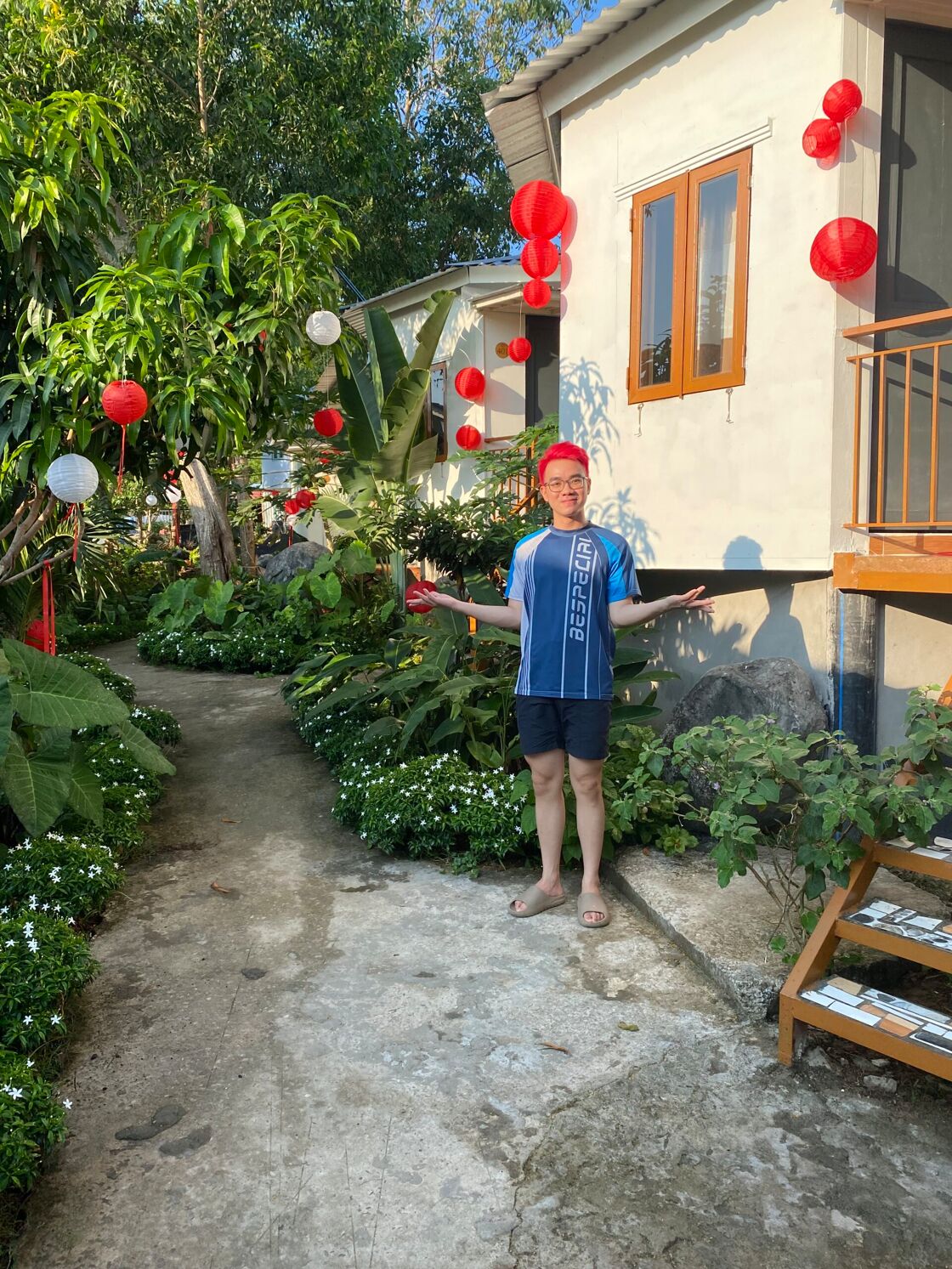 Phat's red hair matches the lanterns  as he poses in the lush garden of his bungalows on Phu Quoc Island Vietnam. 
