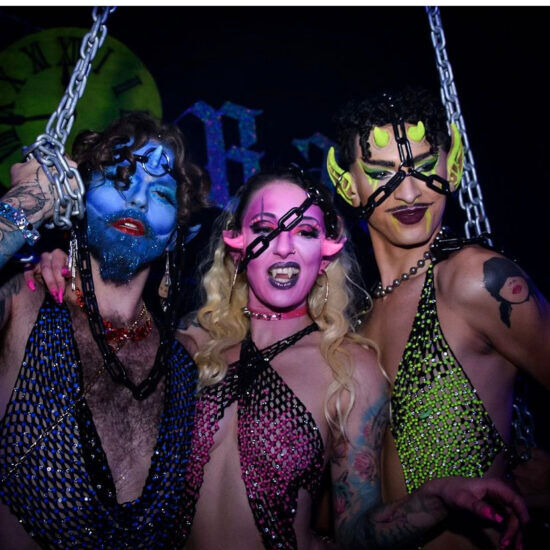 Three sexy  horned gender outlaws in blue, pink, and yellow face-paint pose for the camera at Dad's Ball. 