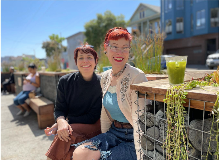Two women with short red hair sit on Pinhole coffee's park-let amongst succulents and an iced matcha.