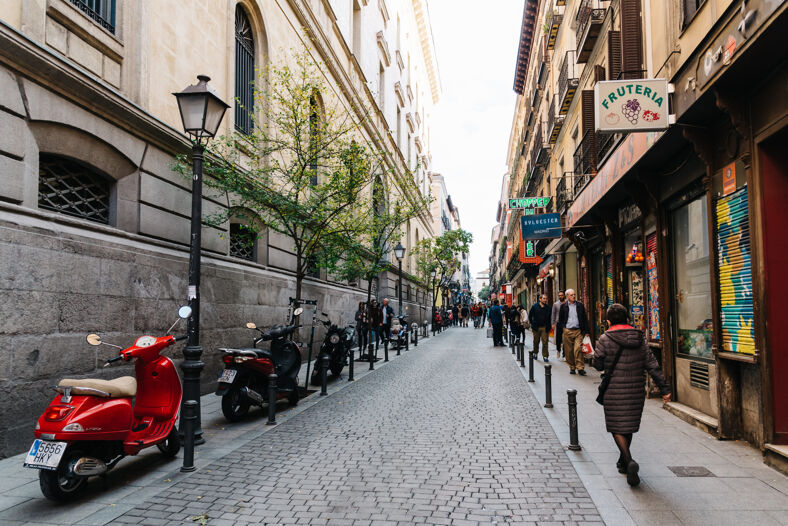 People window shopping down a busy cobblestone street in Madrid's Malasaña neighborhood.