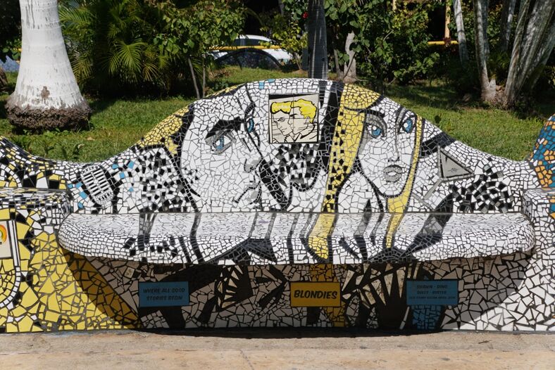 A mosaic covered bench in an urban park.