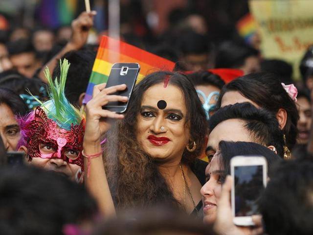 A women takes a photo in the crowd of a pride parade in India.