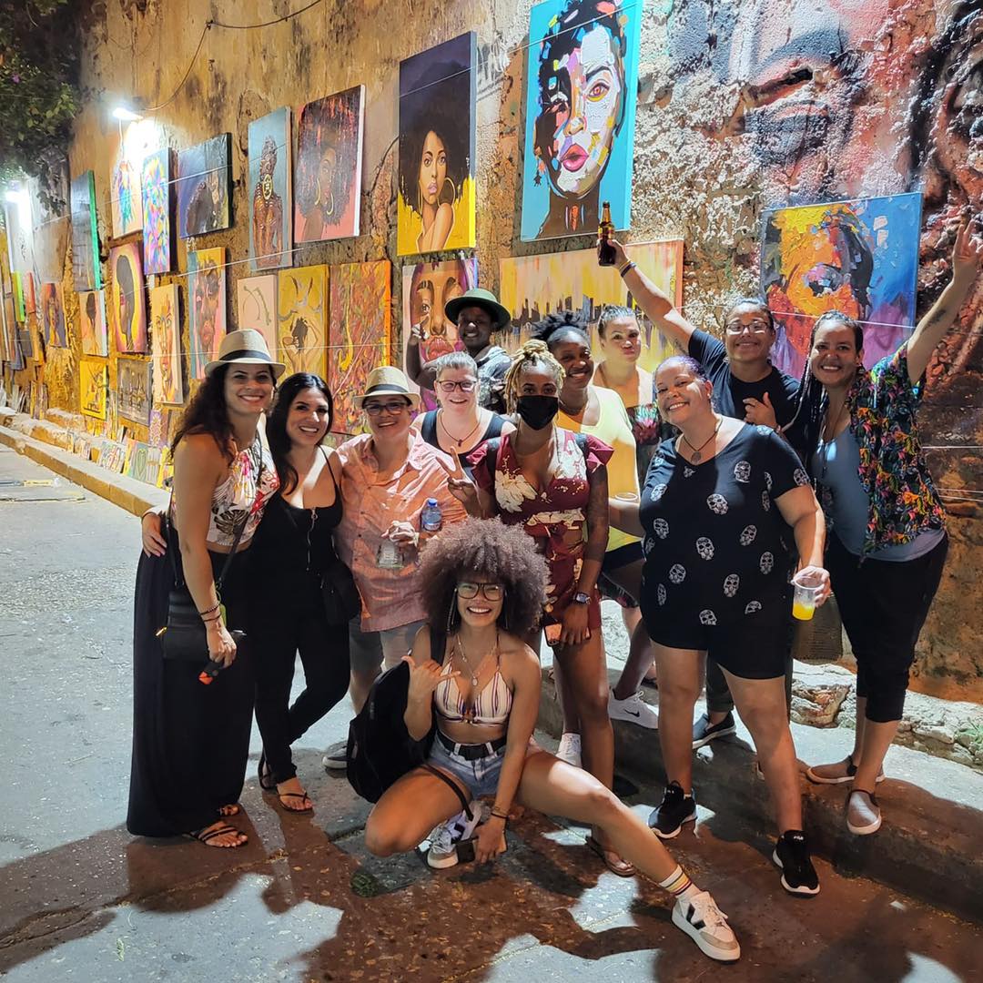 A group of multicultural woman pose in front of a colorful art market in Cartagena, Colombia. 
