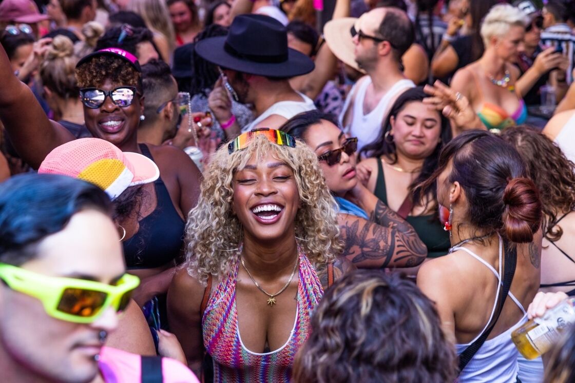 A young Black woman dancing in a crowd.