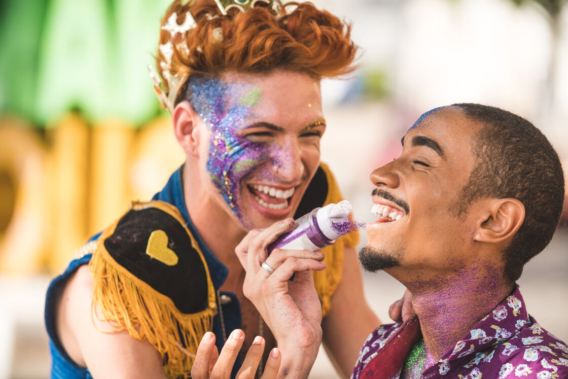 Two men putting on glitter and face paint in preparation for Mardi Gras in New Orleans. 