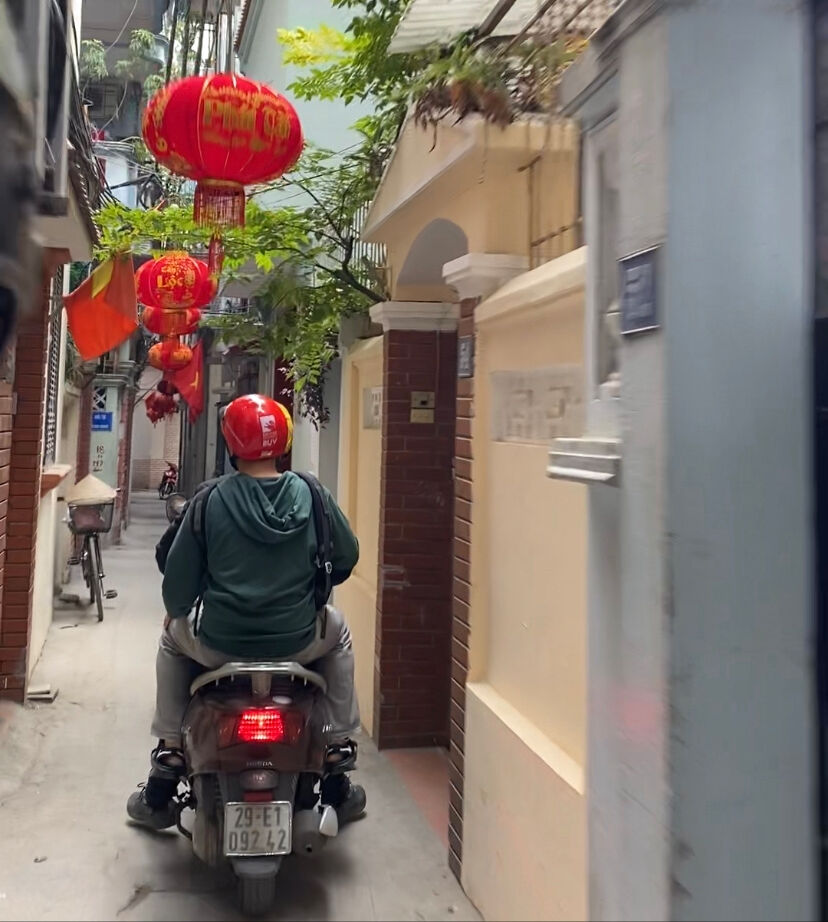 A motorbike cruises through the narrow streets of Hanoi with red lanterns hanging for Tet.
