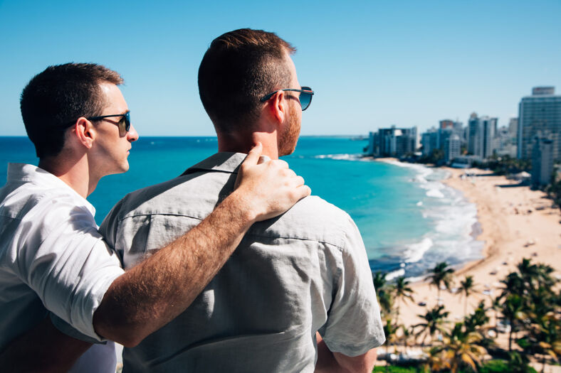 Two men embracing, overlooking the beach.