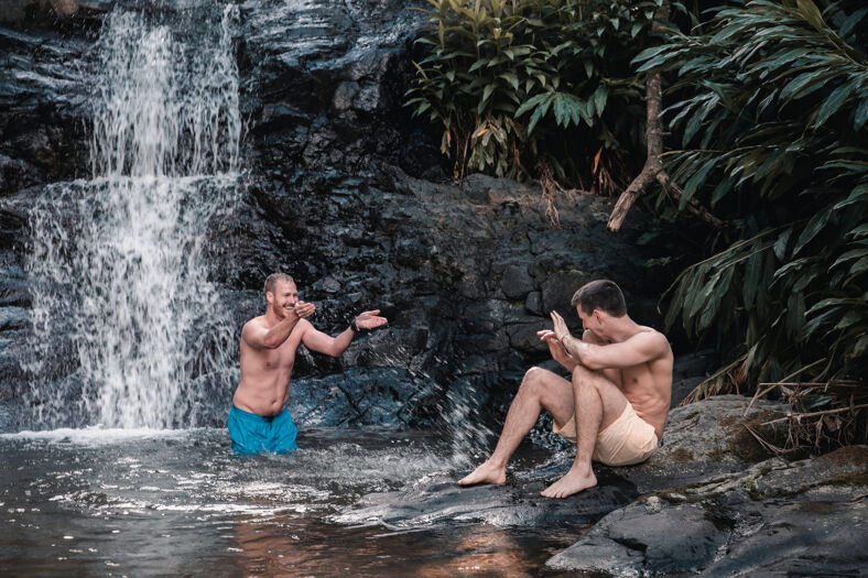 Two men playing in a waterfall.