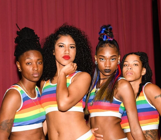 Dancers in rainbow crop tops pose for the camera.