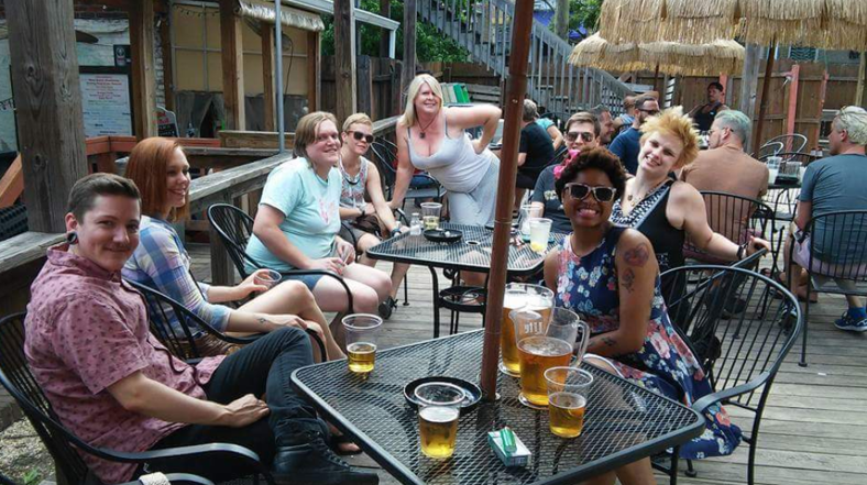 A group of gals enjoying beers on a patio.