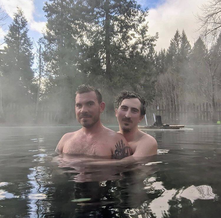 Two men embrace inside of a forest thermal bath in Breitenbush Hot Springs.