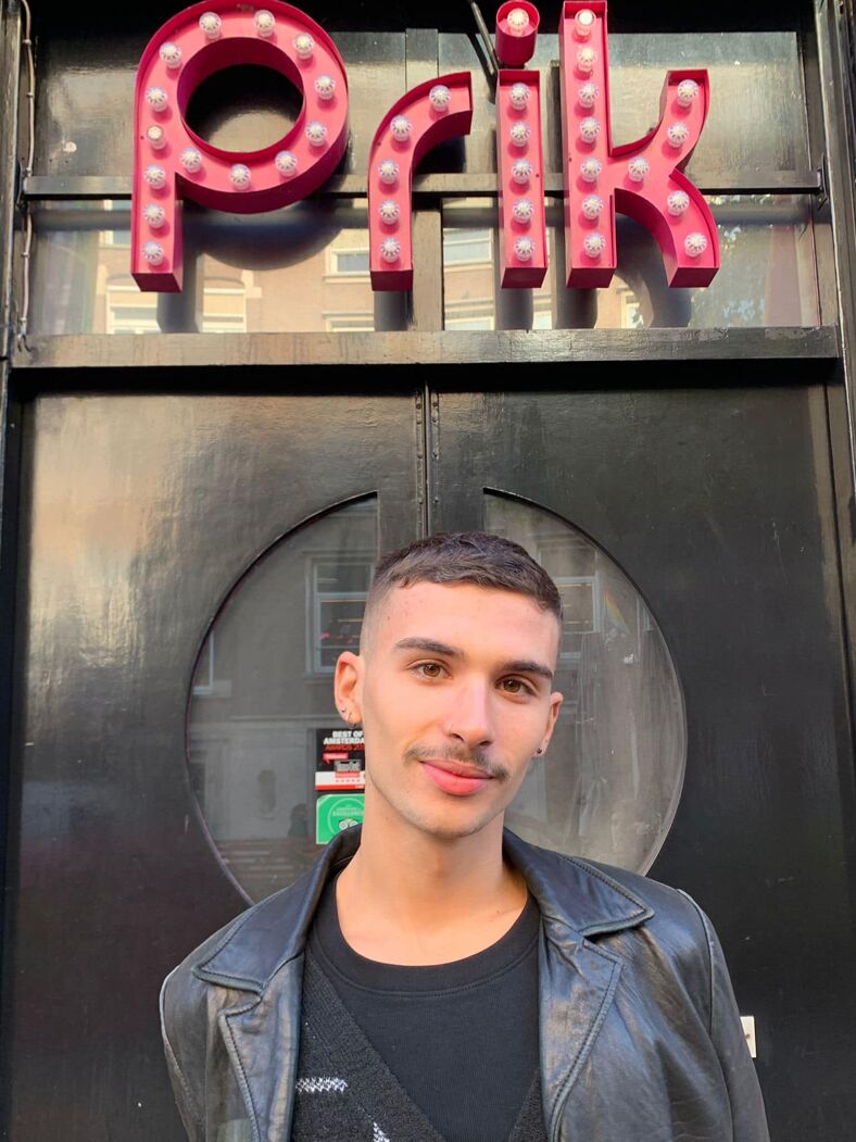 A man in a leather jacket standing outside Prik in Amsterdam.