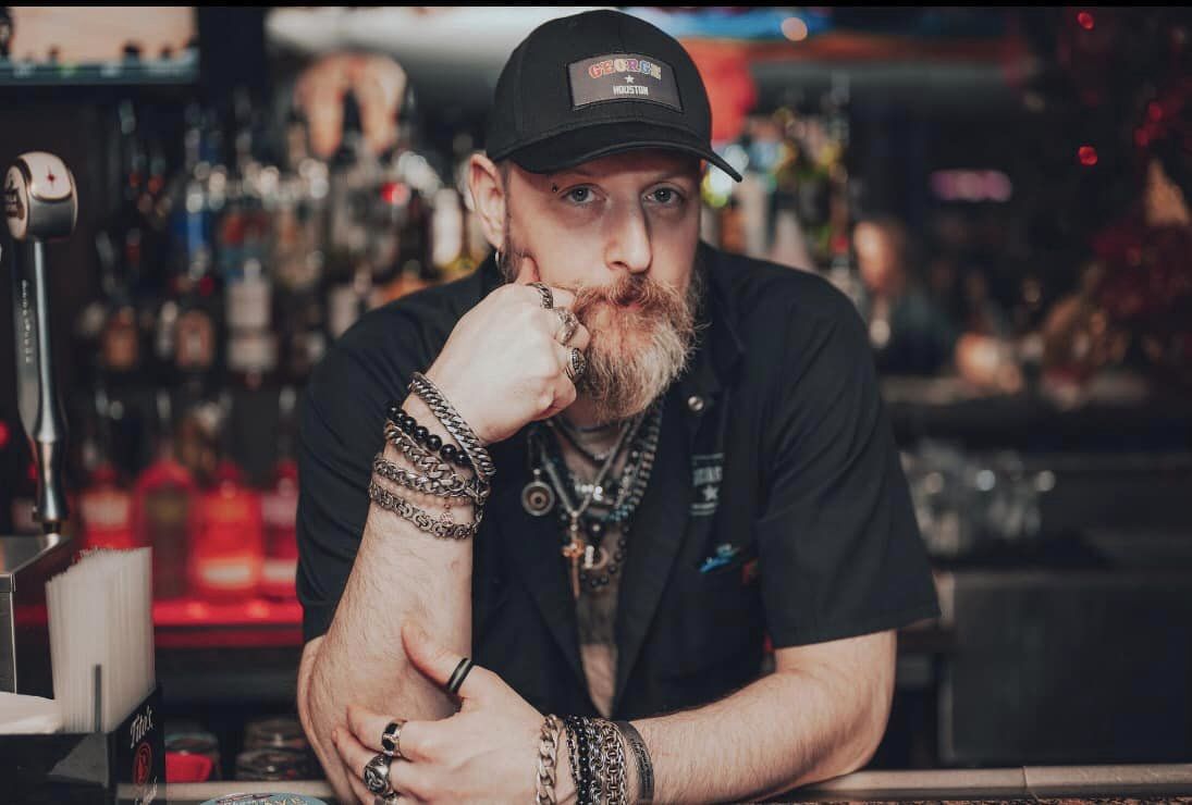 A handsomely disheveled bartender at George in Houston stares peers at the camera with his piercing blue eyes.
