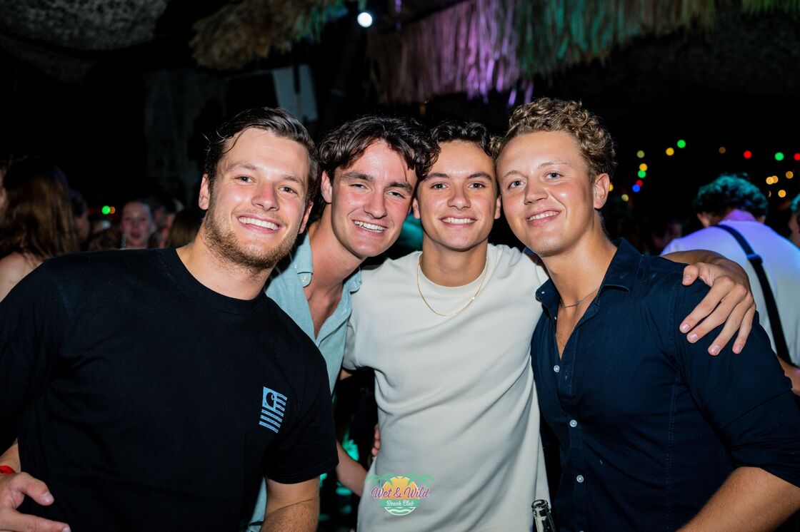 Four guys at a nightclub posing for the camera.