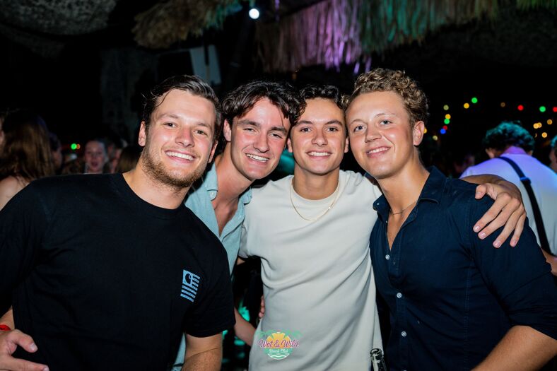Four guys at a nightclub posing for the camera.