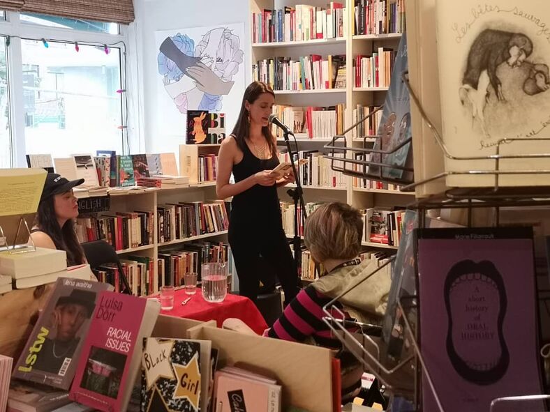 A woman reads a book at a literature event at L'Euguélionne, librairie féministe.
