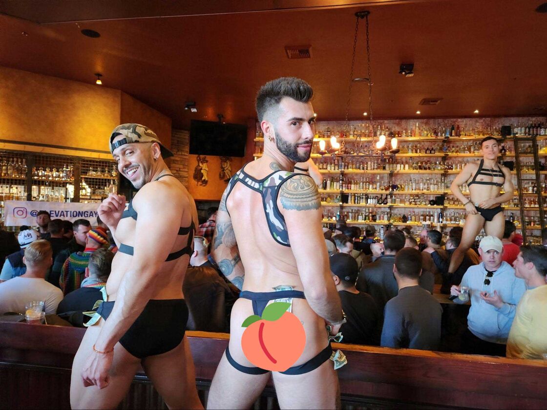 Go-go dancers dressed in harnesses and jockstraps dancing for the crowd.