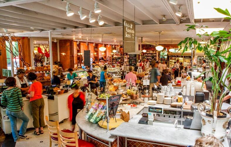 The interior of Elephant Deli with several people shopping and ordering food.