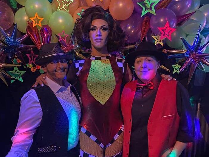 A drag queen poses with fans.
