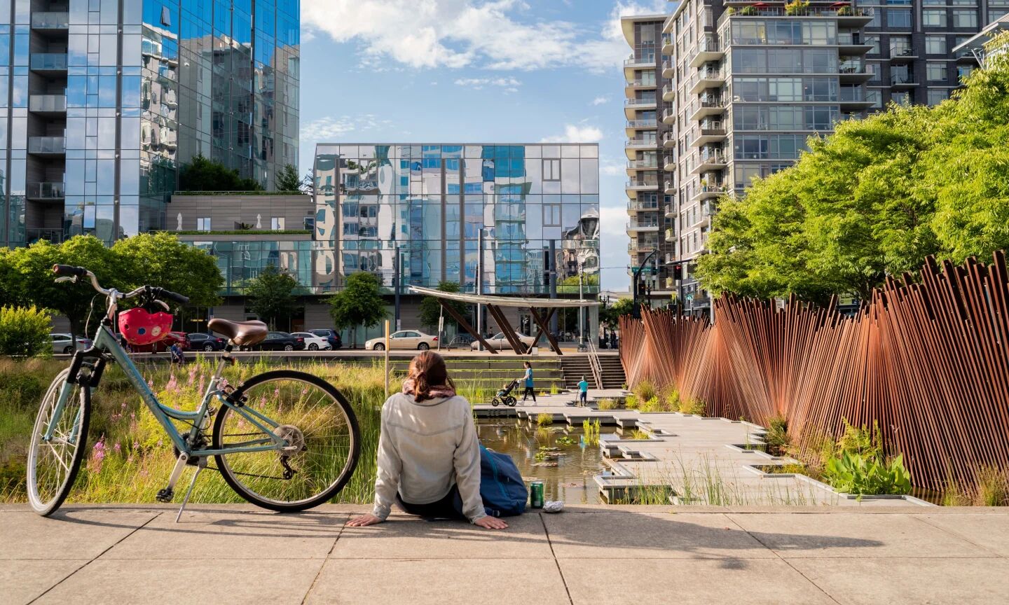 A person relaxing on the ground in a park next to a bicycle.