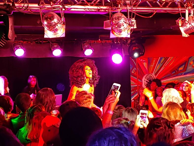 A drag queen sings on stage to an adoring crowd.