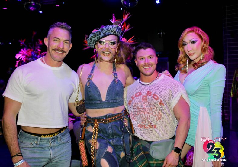 Drag queens pose with fans in the crowd.
