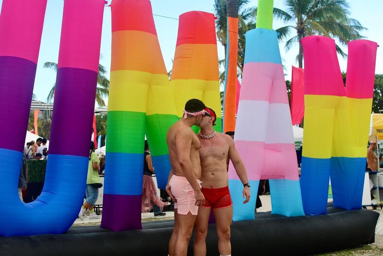 Two shirtless men kissing at Miami Beach Pride.