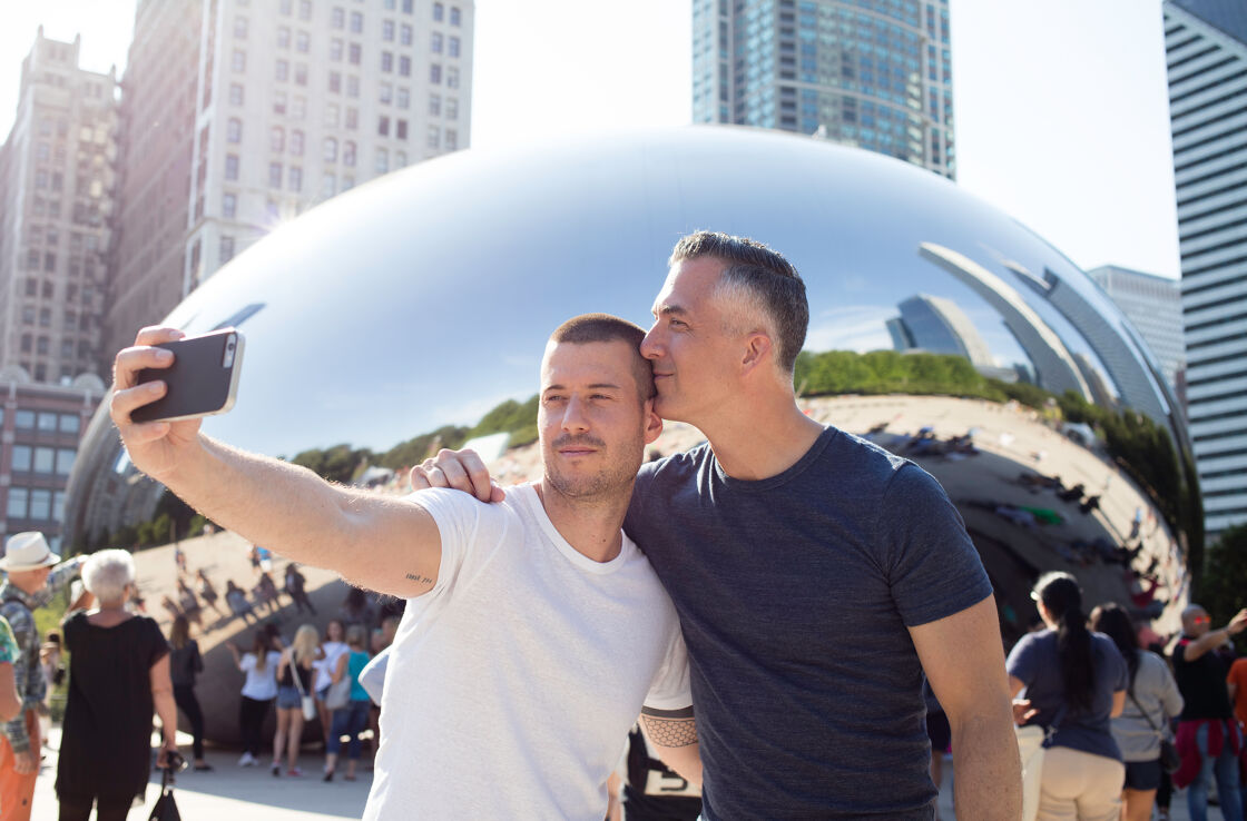 two gay men taking a selfie in front of Chicago's Bean