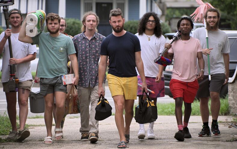 Bobby Berk holds tool bags as he walks with a group of young frat boys.