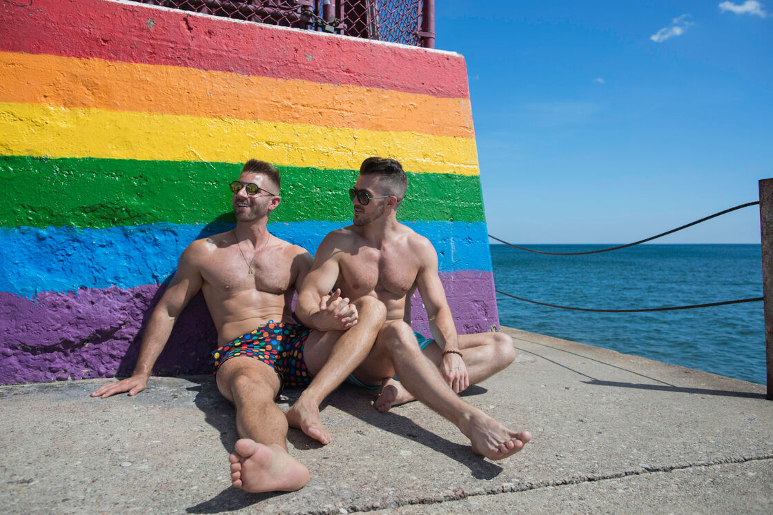 two men sitting at the end of the pier's rainbow-painted landmark at Hollywood Beach