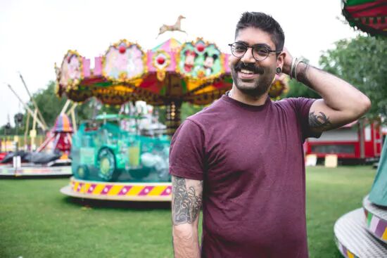 A man smiling in front of an amusement park ride. 