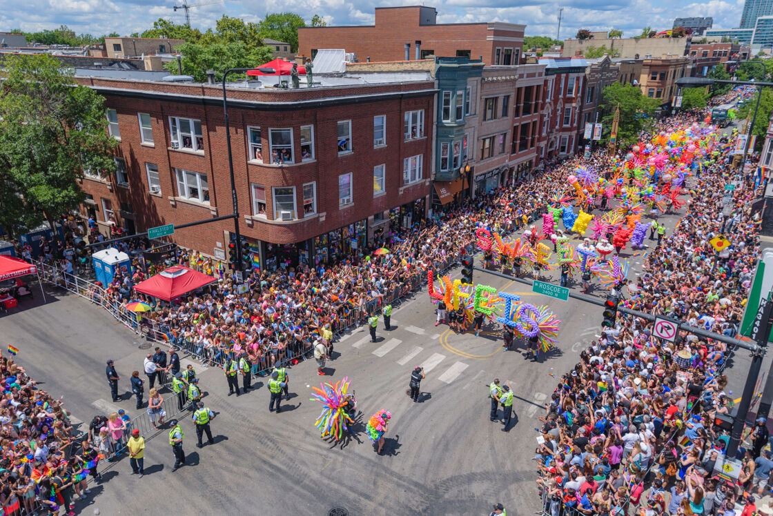 thousands of people line the streets of Northalsted, Chicago during Pride Month in Illinois with colorful floats marching down the road