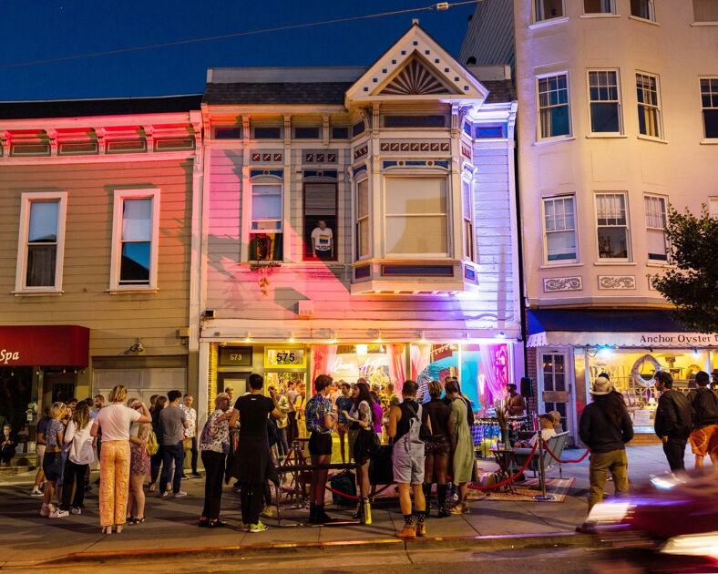 A crowd forms at night outside 575 Castro.