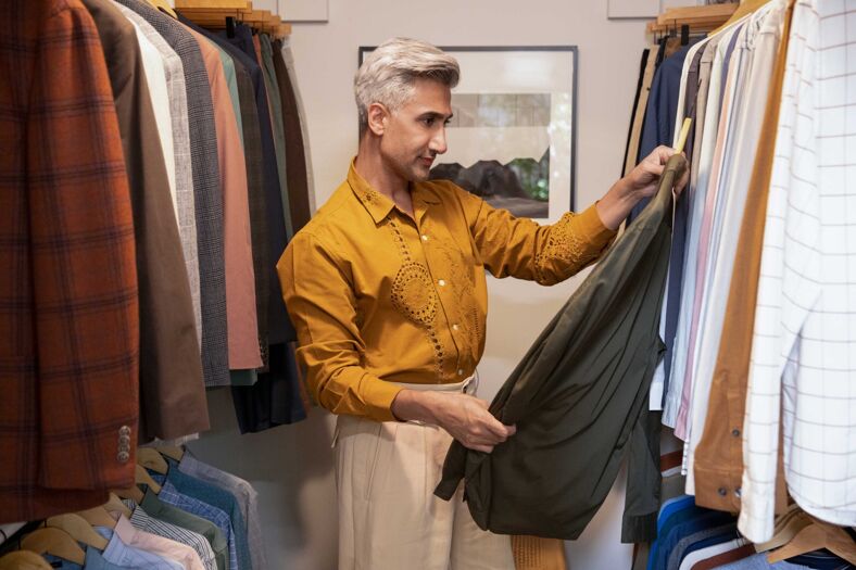 Tan France picks out clothes from a closet. 