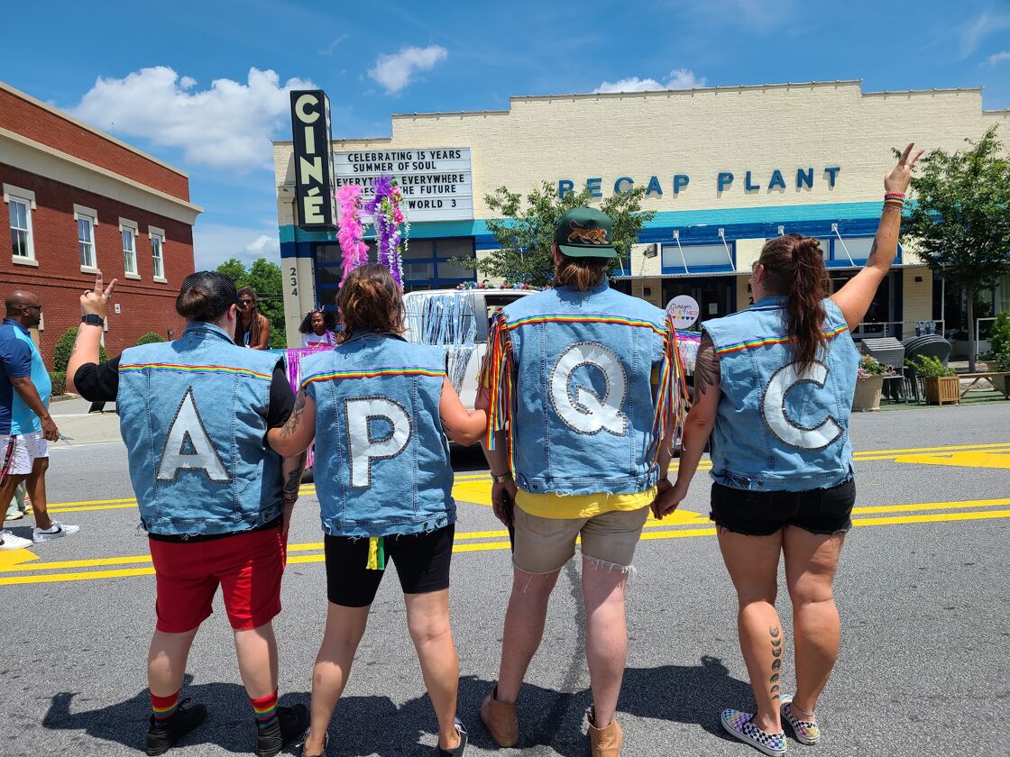 The Athens Pride + Queer Collective team in matching denim vests at Pride.