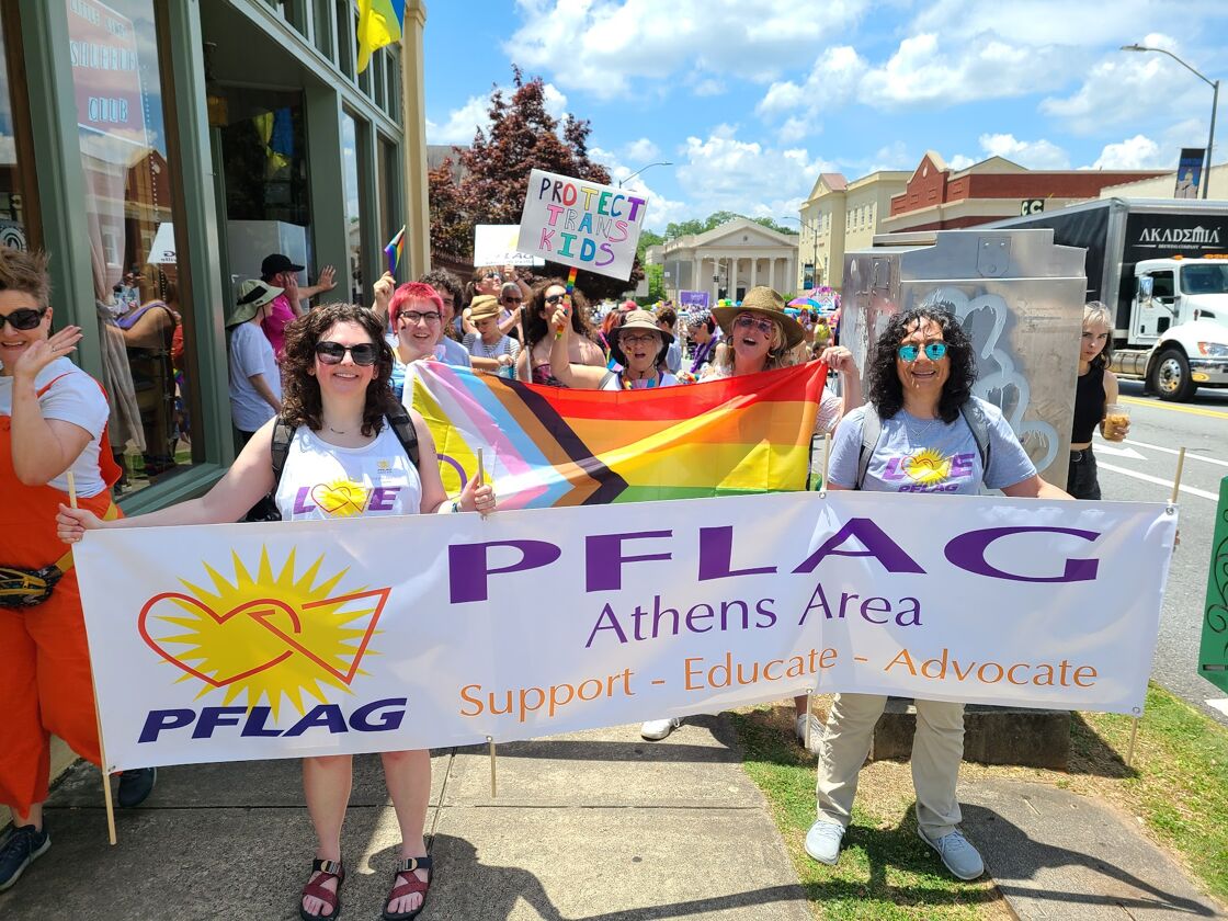 Marchers hold a PFLAG sign.