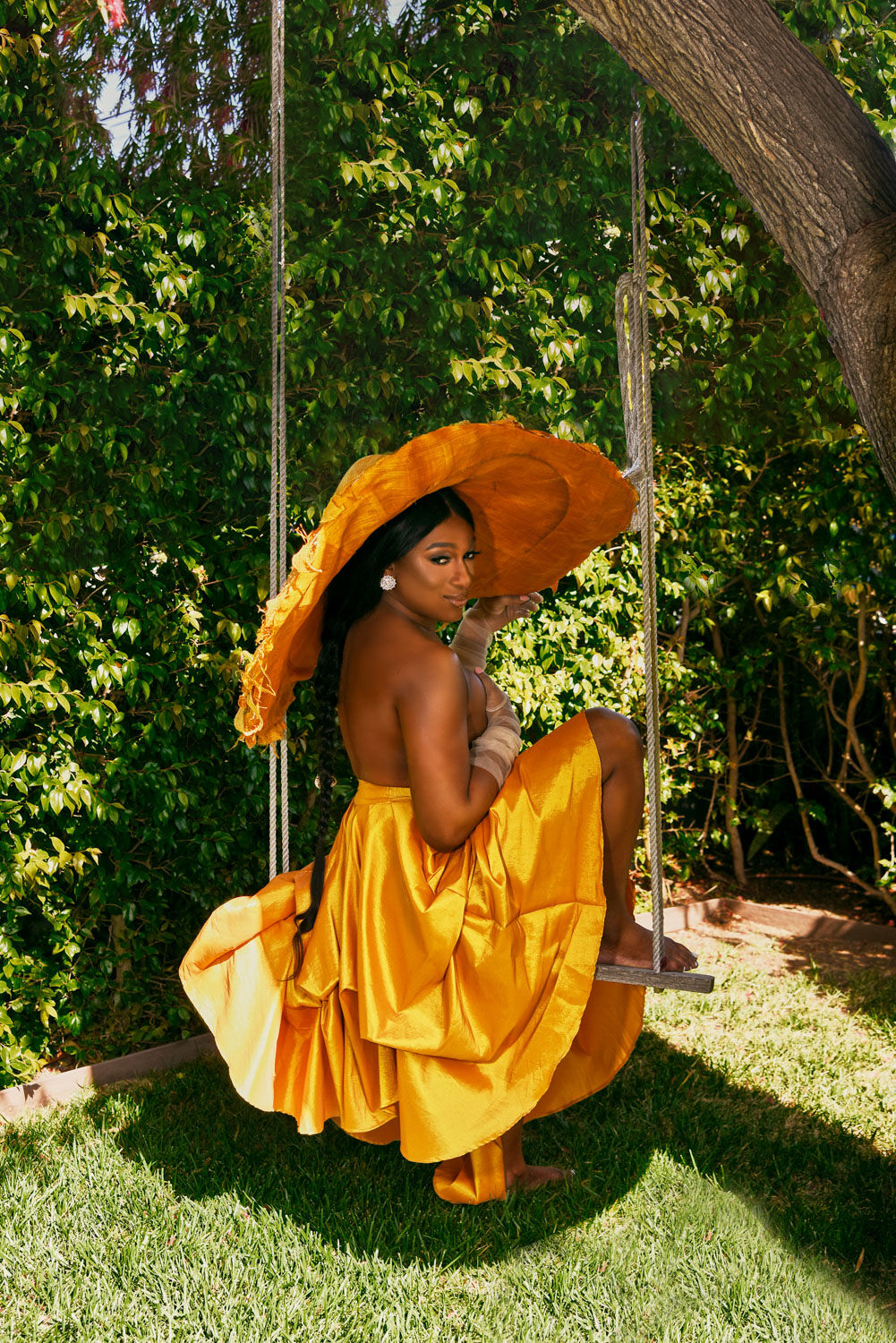 Elle Moxley wearing an orange gown on a swing.