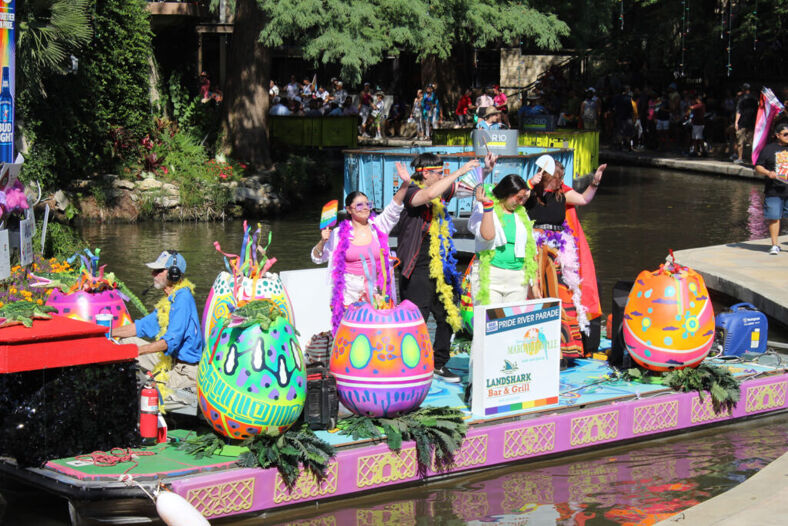 A colorful float filled with smiling, waving people