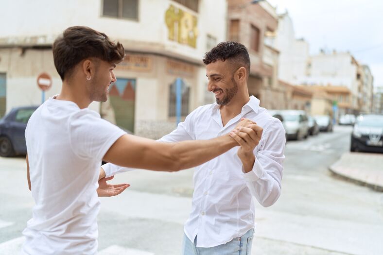 Two men wearing white shirts dancing on the street.