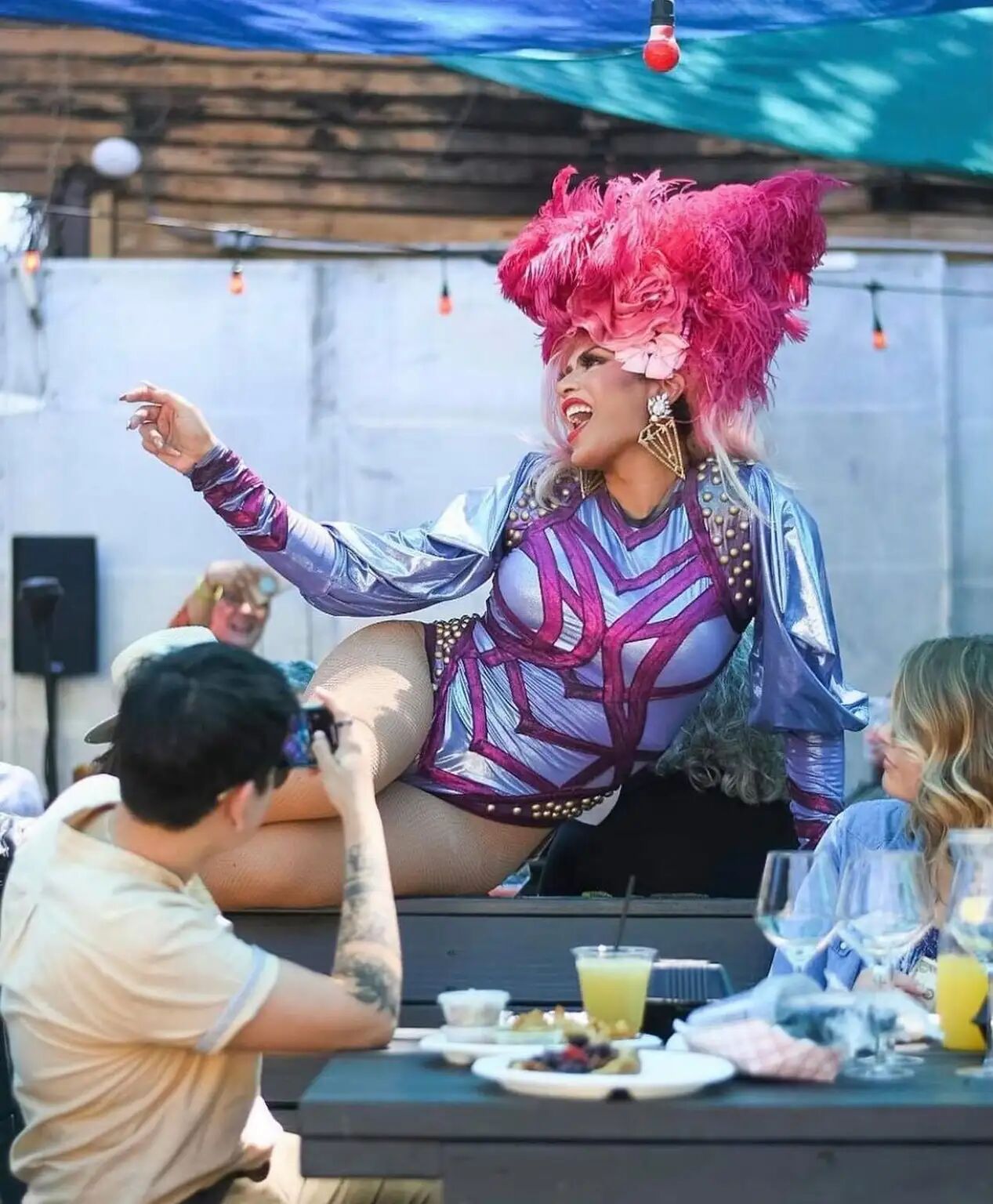 Drag Queen sits on top of a couples table, serenading them