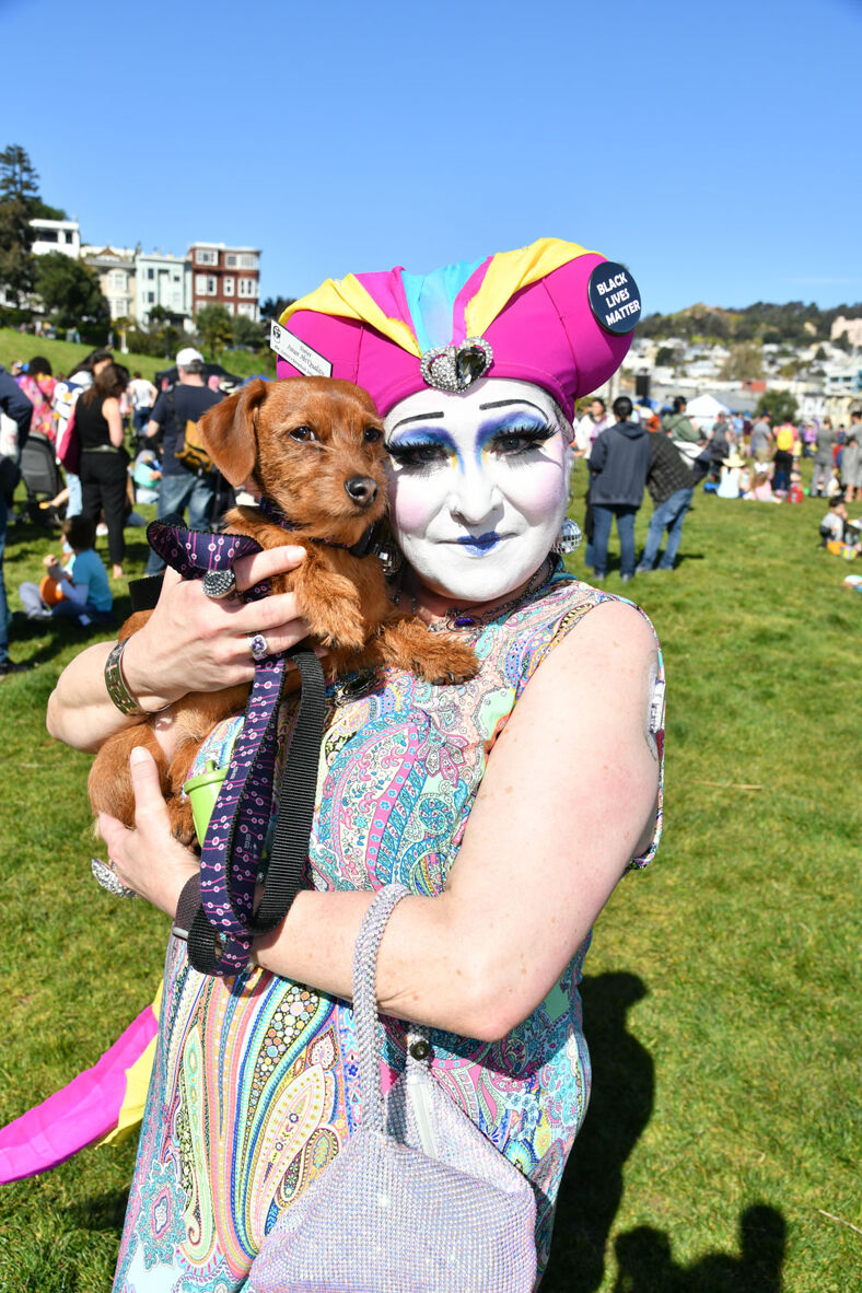 A drag queen holding a puppy in Dolores Park.