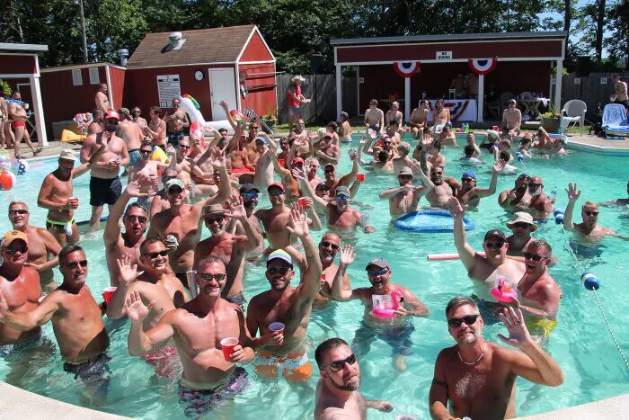 Men in a pool waving at the camera.