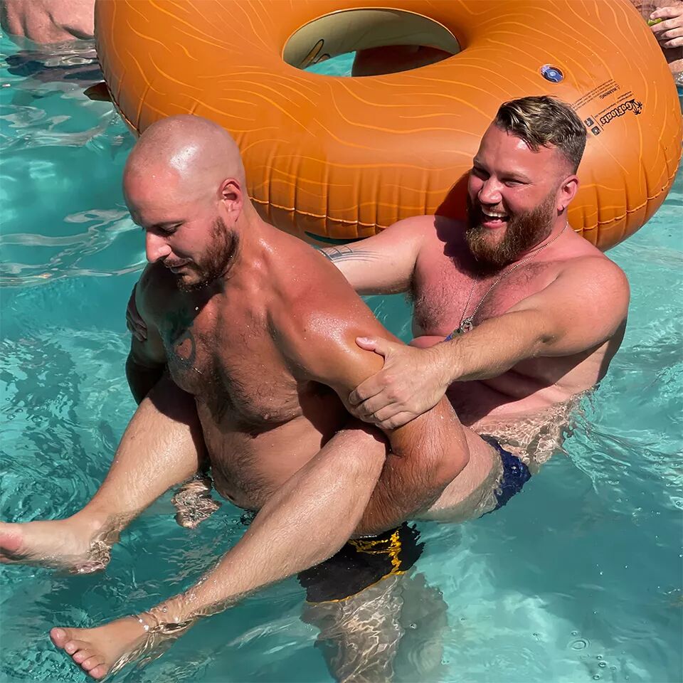 Two men play piggy back in a pool