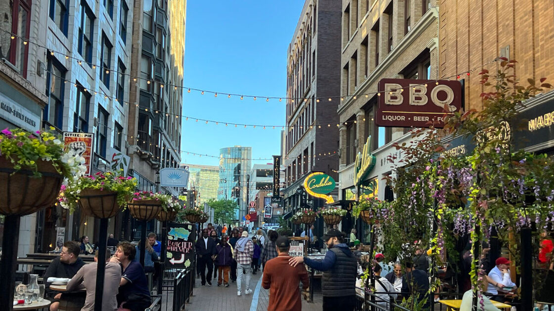 Bustling downtown street with shops and restaurants lining the side. 
