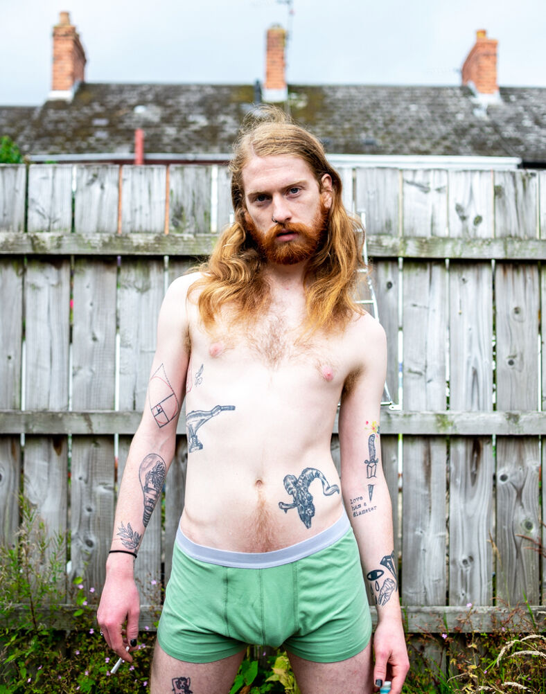A man with long hair and tattoos wearing green boxers