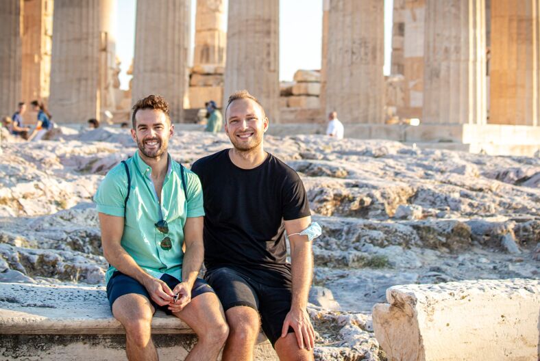 a gay couple sitting in front of european ruins during their LGBTQ+ honeymoon
