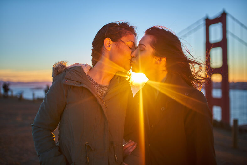a lesbian couple kissing in front of the golden gate bridge in san francisco, california while celebrating their wedding