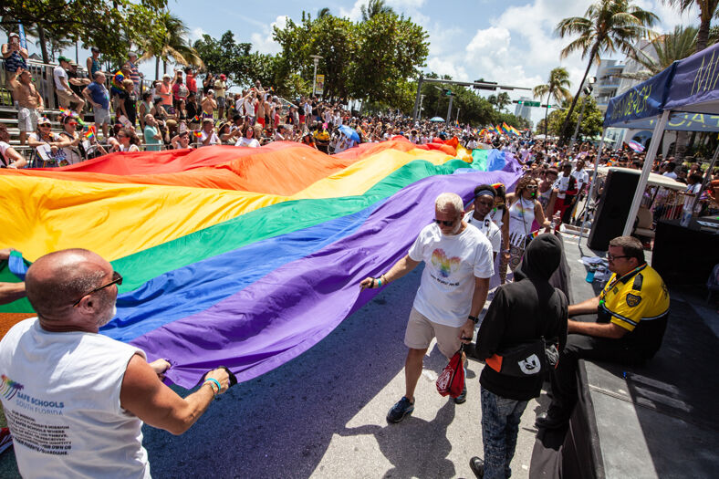 Participants carry a large Pride flag during Miami Beach Pride