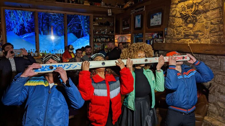 A group of people dressed in ski gear take a shot off a ski